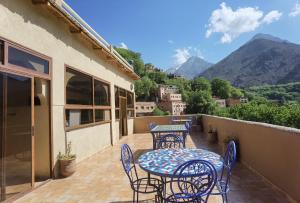a patio with tables and chairs on a balcony with mountains at Riad Atlas Imlil in Imlil