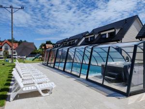 a group of white chairs and a house with windows at Osada Jantar-Resort&SPA in Jantar