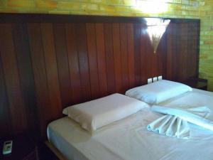 two beds with white sheets and a light on the wall at Pousada do Forte in Barra do Cunhau