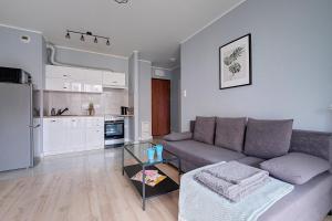 ein Wohnzimmer mit einem Sofa und einer Küche in der Unterkunft 2Br Apt Strzelecka 24 with balcony in Warschau