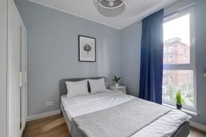ein Schlafzimmer mit einem Bett und einem großen Fenster in der Unterkunft 2Br Apt Strzelecka 24 with balcony in Warschau