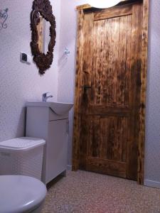 a bathroom with a wooden door with a toilet and a sink at Podroże Chëcz in Charbrowo