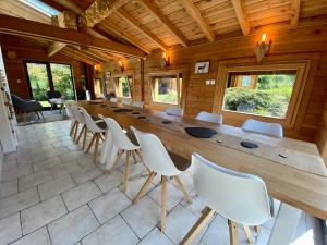 een lange houten tafel en stoelen in een kamer bij Gîte Chalet avec bain nordique et piscine 11 pers Hautes Vosges in Plainfaing