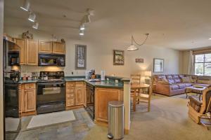 a kitchen with wooden cabinets and a living room at Cozy Ski-In and Ski-Out Winter Park Resort Condo! in Winter Park