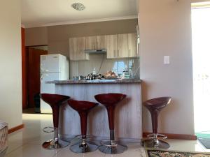 a kitchen with red bar stools in front of a counter at manu'z in Cape Town