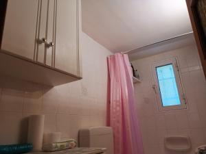 a bathroom with a pink shower curtain and a window at Perithia Cottage in Perítheia
