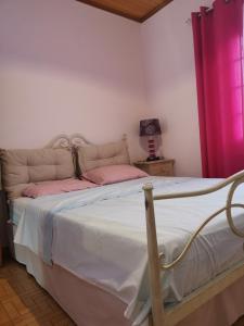 a bedroom with a bed with pink pillows at Perithia Cottage in Perítheia