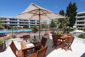 a patio with an umbrella and tables and chairs at Marina Club Lagos Resort in Lagos