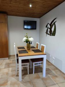 uma mesa de jantar com cadeiras e uma televisão na parede em Casas de Santo António - A em Odeceixe