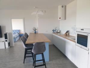 a kitchen with white cabinets and a wooden table and chairs at Apartament Pod Żaglami in Zegrze Południowe