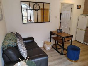 a living room with a black leather couch and a table at Cosy Flat in a Pretty Town. in Crewkerne