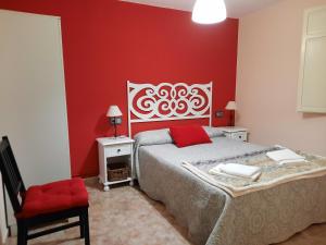 ein Schlafzimmer mit einem Bett und einer roten Wand in der Unterkunft casa carballal in Lorenzana