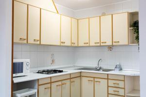 een keuken met houten kasten, een wastafel en een magnetron bij APARTAMENTS ROIG in Benasal