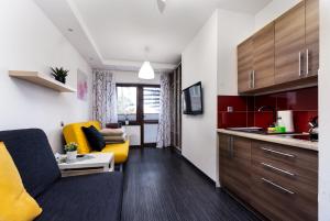 a living room with a yellow couch and a kitchen at Villa Lordis in Krynica Morska