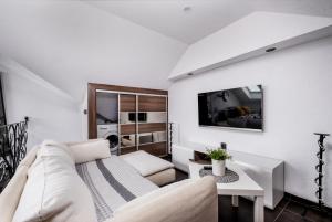 a white living room with a couch and a table at Villa Lordis in Krynica Morska
