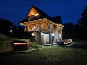 una cabaña de madera por la noche con luces encendidas en Cinalkowa 6, na Górze Żar, en Międzybrodzie Żywieckie