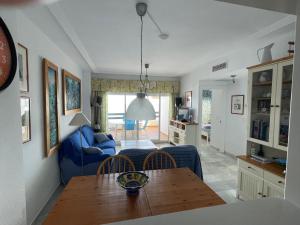 Una sala de estar con una mesa y un sofá azul. en Cala Marina, en La Herradura