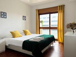 Un dormitorio con una cama con sábanas amarillas y verdes y una ventana en Boavista YourHome, en Oporto