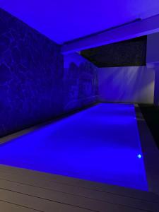 una piscina in una stanza con illuminazione blu di Hotel Château Georgette a Pombas