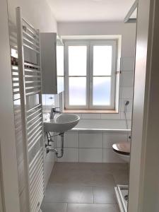 ein weißes Badezimmer mit einem Waschbecken und einer Badewanne in der Unterkunft Apartment Am Jakobsweg in Erfurt
