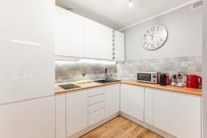 una cocina con armarios blancos y un reloj en la pared en AP Apartments Piastowska en Gdansk