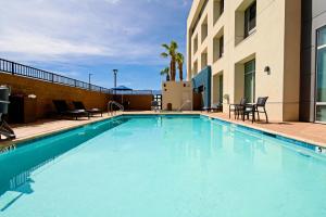 Holiday Inn Express & Suites Palm Desert - Millennium, an IHG Hotel في بالم ديزرت: مسبح ازرق كبير مع كراسي ومبنى