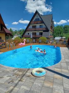 um grupo de pessoas numa piscina com uma casa em Willa Siklawa em Zakopane