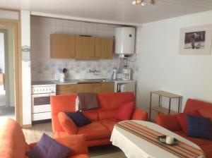 a living room with an orange couch and a kitchen at FH Mecklenburg in Dorf Mecklenburg