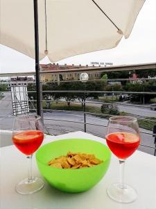 un bol vert de chips et deux verres de vin dans l'établissement Orizzonte Marino - Giallo: Angolo solare verso la laguna, cod027044-loc-01086, à Cavallino-Treporti