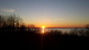 a sunset over a body of water with the sun setting at P-4 in Retowo +2 photos