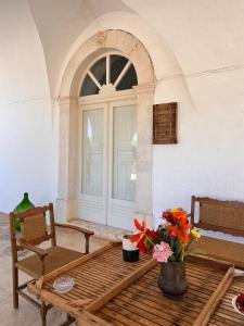 un porche con mesa, silla y flores en Masseria Concorrano, en Castellana Grotte