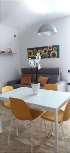 une table blanche avec des chaises jaunes et un vase blanc avec des fleurs dans l'établissement Orizzonte Marino - Giallo: Angolo solare verso la laguna, cod027044-loc-01086, à Cavallino-Treporti