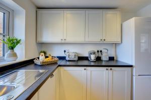 a kitchen with white cabinets and a white refrigerator at Kist Accommodates - Duck Hill Cottage in Ripon