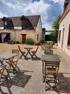 a group of wooden tables and chairs in front of a building at La Maison Genevier - Chambre Doréline in Montreuil-en-Touraine