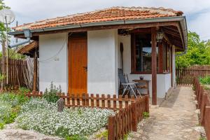 une petite maison blanche avec une porte en bois dans l'établissement Къщата с Кладенеца - с. Генерал Кантарджиево, à General-Kantardzhievo