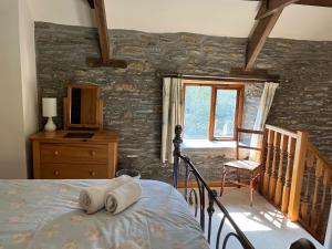 um quarto com uma cama e uma parede de pedra em Troedyrhiw Holiday Cottages em Cardigan