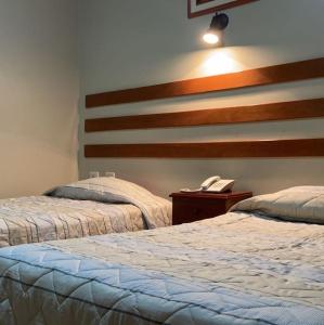 2 camas en una habitación con teléfono en una mesa en Hotel Begonias en Lambayeque