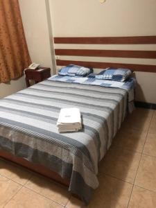 a bedroom with a bed with blue and white sheets at Hotel Begonias in Lambayeque