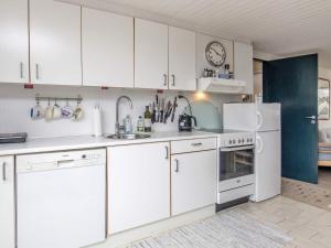 uma cozinha com armários brancos, um lavatório e um frigorífico em Holiday home Otterup VIII em Otterup
