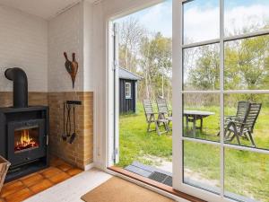 a living room with a fireplace and a patio with chairs at 6 person holiday home in Bindslev in Bindslev