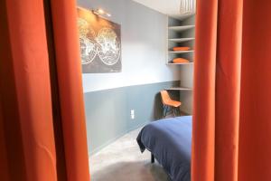- une chambre avec des rideaux orange, un lit et une chaise dans l'établissement Le Victorien, T2 hypercentre chic et cosy, Wifi par SOVALFI, à Saint-Étienne