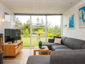a living room with a couch and a large window at 7 person holiday home in Ulfborg in Fjand Gårde