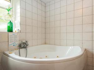 uma banheira na casa de banho com azulejos brancos em 7 person holiday home in Ulfborg em Fjand Gårde