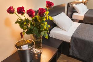 un jarrón de rosas sobre una mesa en una habitación de hotel en Family Hotel Pautalia, en Sandanski