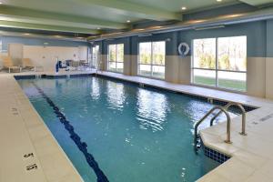 a large swimming pool with blue water and windows at Holiday Inn Express & Suites - Brighton South - US 23, an IHG Hotel in Brighton