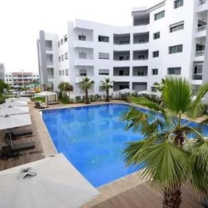 Appartement la Siesta beach resort Mohammedia في المحمدية: مسبح كبير امام مبنى كبير
