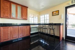 uma cozinha com armários de madeira e bancos de balcão pretos em Solaire Inn & Suites em Santa Maria