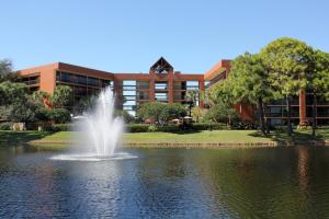 a fountain in the middle of a pond in front of a building at Rosen Inn Lake Buena Vista in Orlando