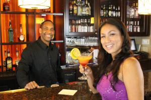 a man and a woman standing at a bar with a drink at Rosen Inn Lake Buena Vista in Orlando