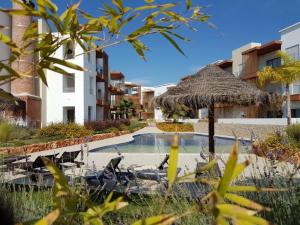 een zwembad met een rieten parasol en stoelen bij Terraços do Rio in Portimão